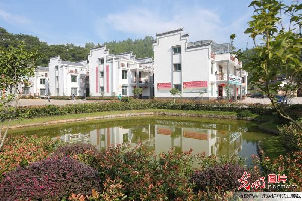 江西省瑞金市叶坪乡黄沙村华屋村小组是有名的红军村,现在已经建成成片楼房,村民实现安居梦。 光明日报记者赵洪波摄/光明图片 青松依旧在,不见儿郎归。在长征途中,华屋籍17名青年全部牺牲。这些松树后来被乡亲们叫作信念树,目的是激励一代代华屋人铭记先烈们的精神,苦干实干,早日走上致富路。 因为革命,华屋很红;因为战争,华屋也很穷。村民华盛向记者描述了4年前的华屋旧貌,全村119户中有103户居住在透风漏雨的土坯房中,土灶台、木板床,没有一户家庭有卫生间。 2012年,国务院出台《国务